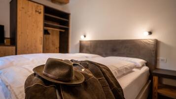 Cama con sombrero y chaqueta marrones, armario de madera y cabecera con luces.
