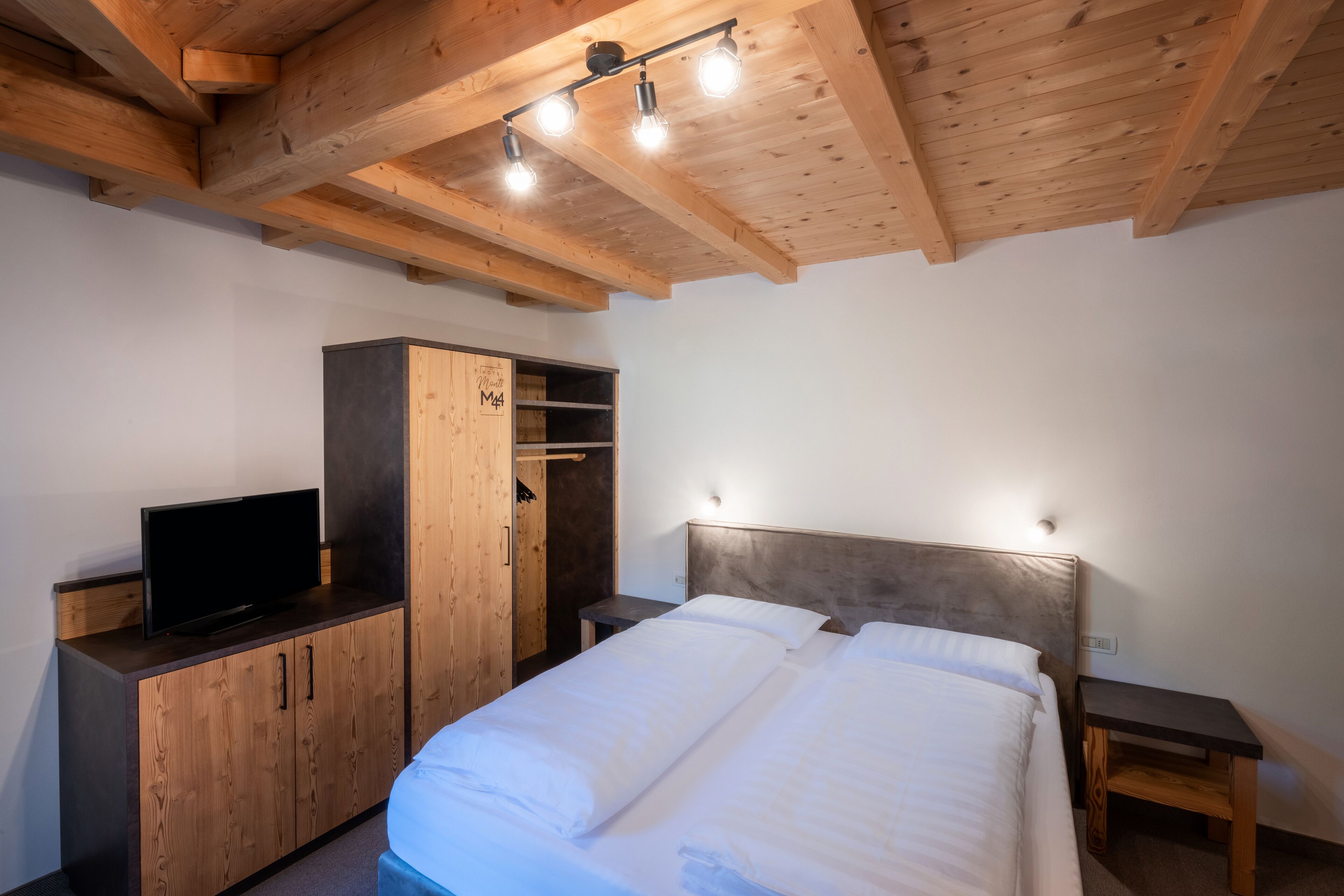 Ein Schlafzimmer mit einem Bett, einem Holzschrank und einem Fernseher auf einem Schrank.