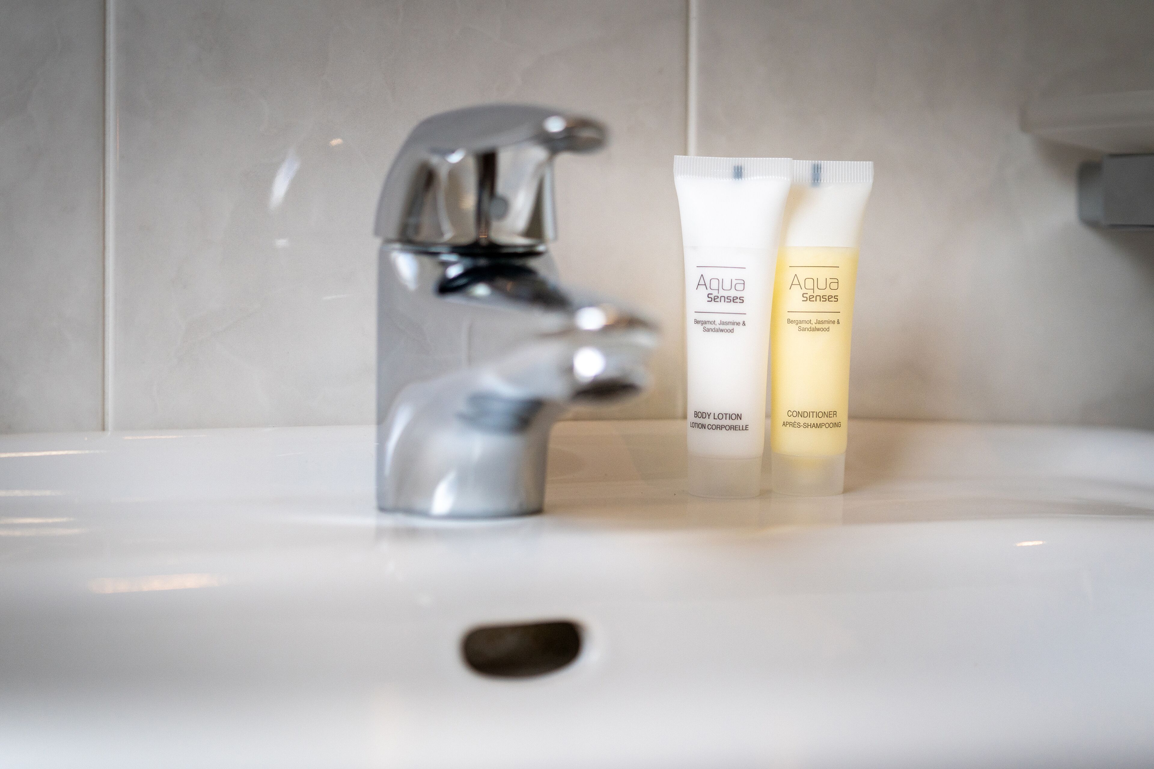 Een badkamermeubel met een moderne kraan en twee flesjes Aqua Senses body lotion.