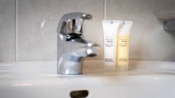 Een badkamermeubel met een moderne kraan en twee flesjes Aqua Senses body lotion.