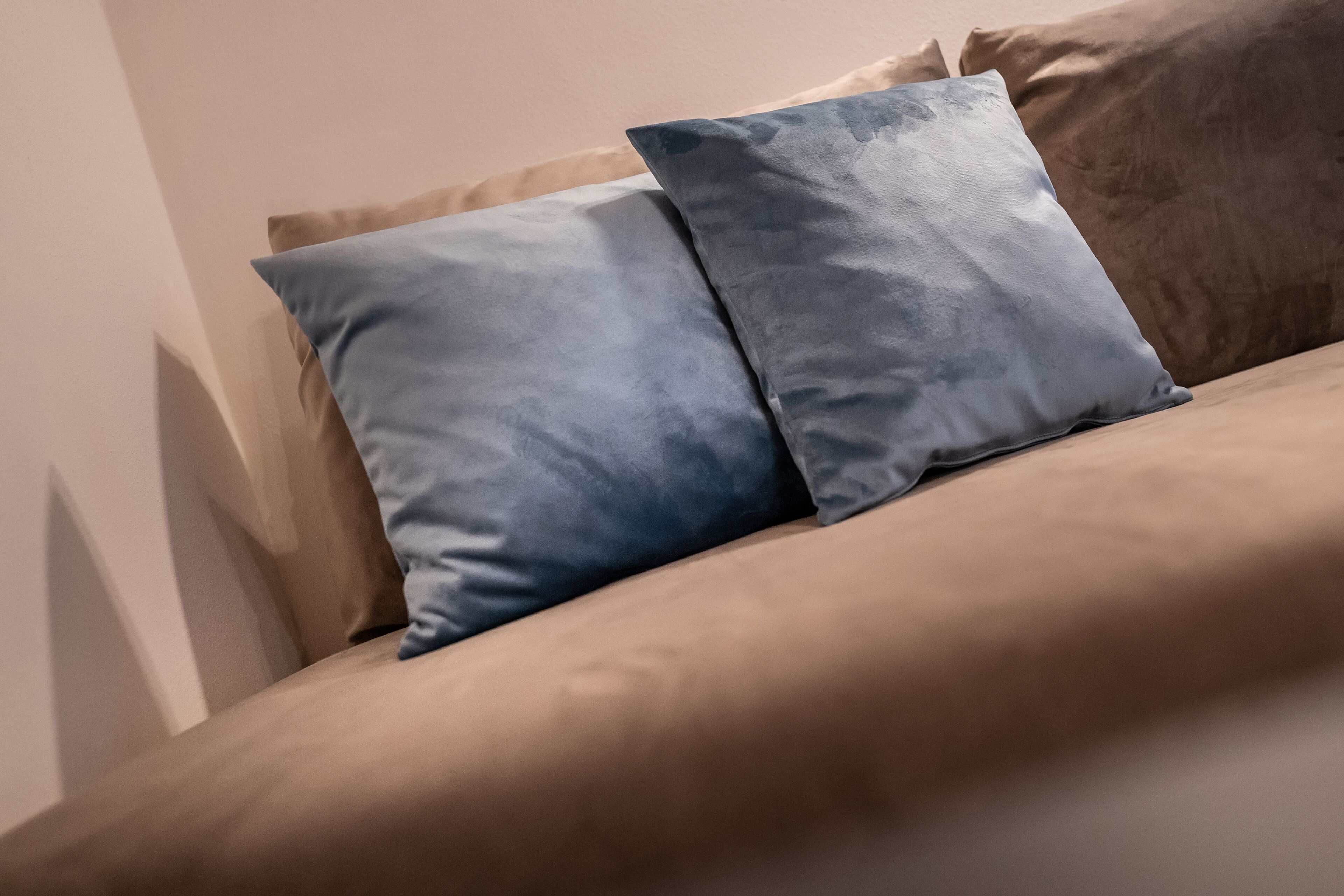 Una cama con un colchón color crema y dos almohadas, una azul claro y otra azul oscuro.