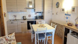 Ett modernt kök med ljusa träskåp, en köksö med sittplatser och ett matbord med stolar.