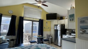 A compact kitchen with a refrigerator, stove, and dining area. - Come and Relax at Paradise Found! (HATTERAS)
