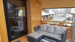 Un'area salotto esterna coperta con mobili in vimini e una porta in vetro.