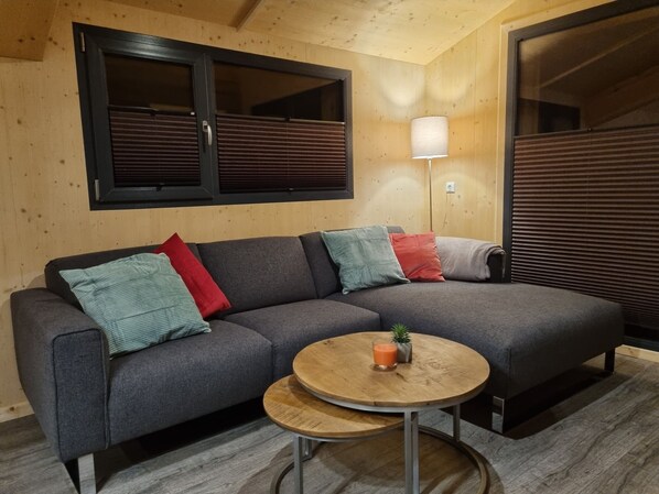 A modern living room with a grey sectional sofa, a small wooden table, and a lamp.
