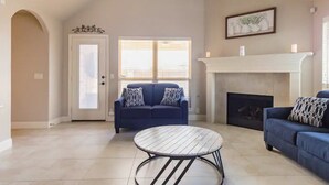 A spacious living room with a fireplace, a blue sofa, and a round coffee table.
