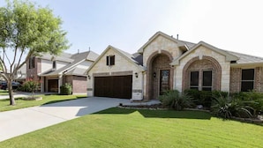 A residential house with a stone facade, a brick entrance, and a well-maintained lawn.