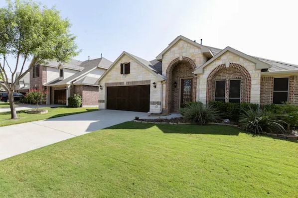 A residential house with a stone facade, a brick entrance, and a well-maintained lawn. - Beautiful 5BD/3BA Near BLD/Waterpark/AT&T Stadium (Mansfield)