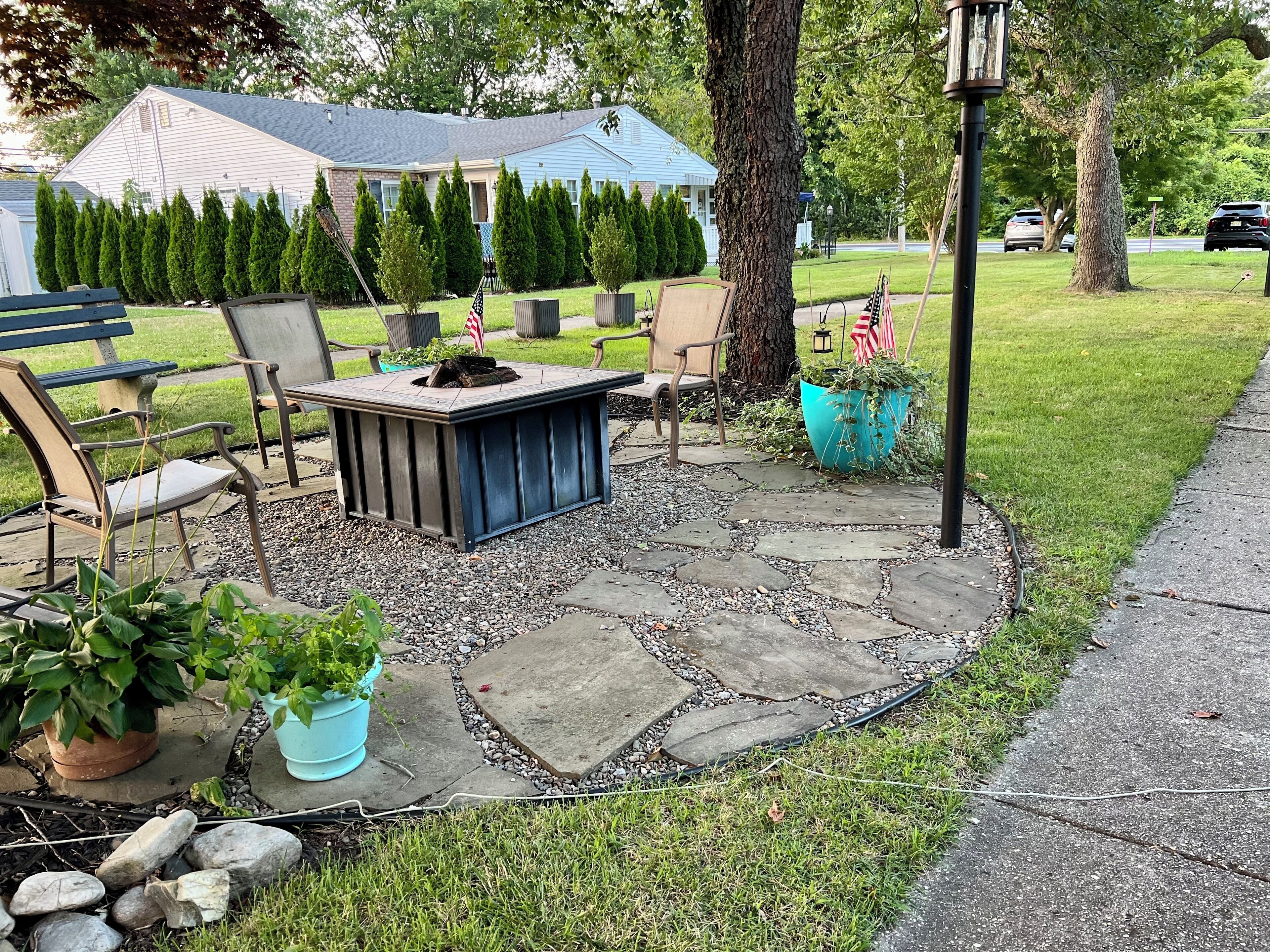 Un espace patio doté d’un sol en pierre, de mobilier d’extérieur et de plantes en pot.