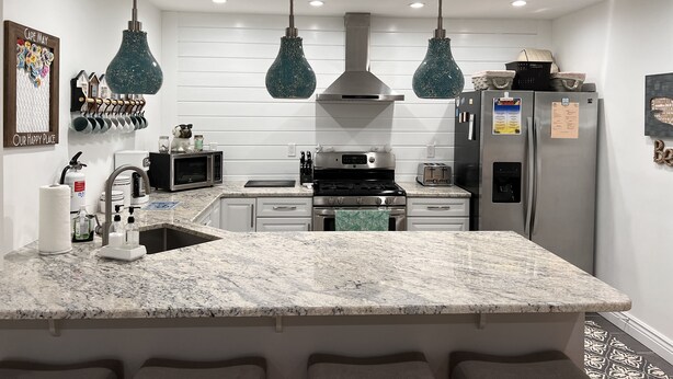 Una cucina moderna con un piano di lavoro in granito, elettrodomestici in acciaio inossidabile e lampade a sospensione.