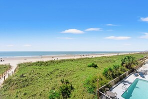 A beach view with a swimming pool and lounge chairs. - Dunescape 201-3BR/2.5BA Oceanfront condo in Crescent Beach (North Myrtle Beach)