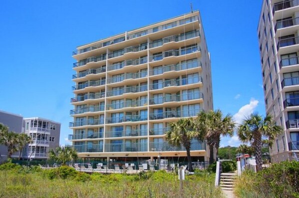 A multi-story hotel with balconies, a central courtyard, and a clear sky.
