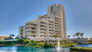 A multi-story hotel with a pool and fountain, surrounded by greenery and palm trees. - Ocean Creek North G5-2BR/2BA Oceanfront condo in Windy Hill (Myrtle Beach)