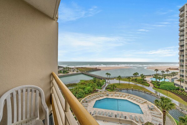 A balcony with a view of a beach, a pool, and a resort area. - Ocean Creek North G5-2BR/2BA Oceanfront condo in Windy Hill (Myrtle Beach)