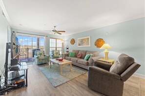 Un salon comprenant un canapé, des fauteuils, une table basse, un téléviseur et un ventilateur de plafond.