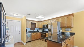 A kitchen with wooden cabinets, a stainless steel refrigerator, a microwave, and a stove. - Ocean Terrace I D3-2BR/2BA Condo in Cherry Grove (North Myrtle Beach)