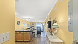 A kitchen with wooden cabinets, a dining area with a table and chairs, and a view to the living room. - Ocean Terrace I D3-2BR/2BA Condo in Cherry Grove (North Myrtle Beach)