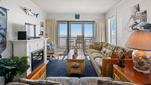 A living room with a fireplace, a large window with a view, a sofa, and a coffee table.