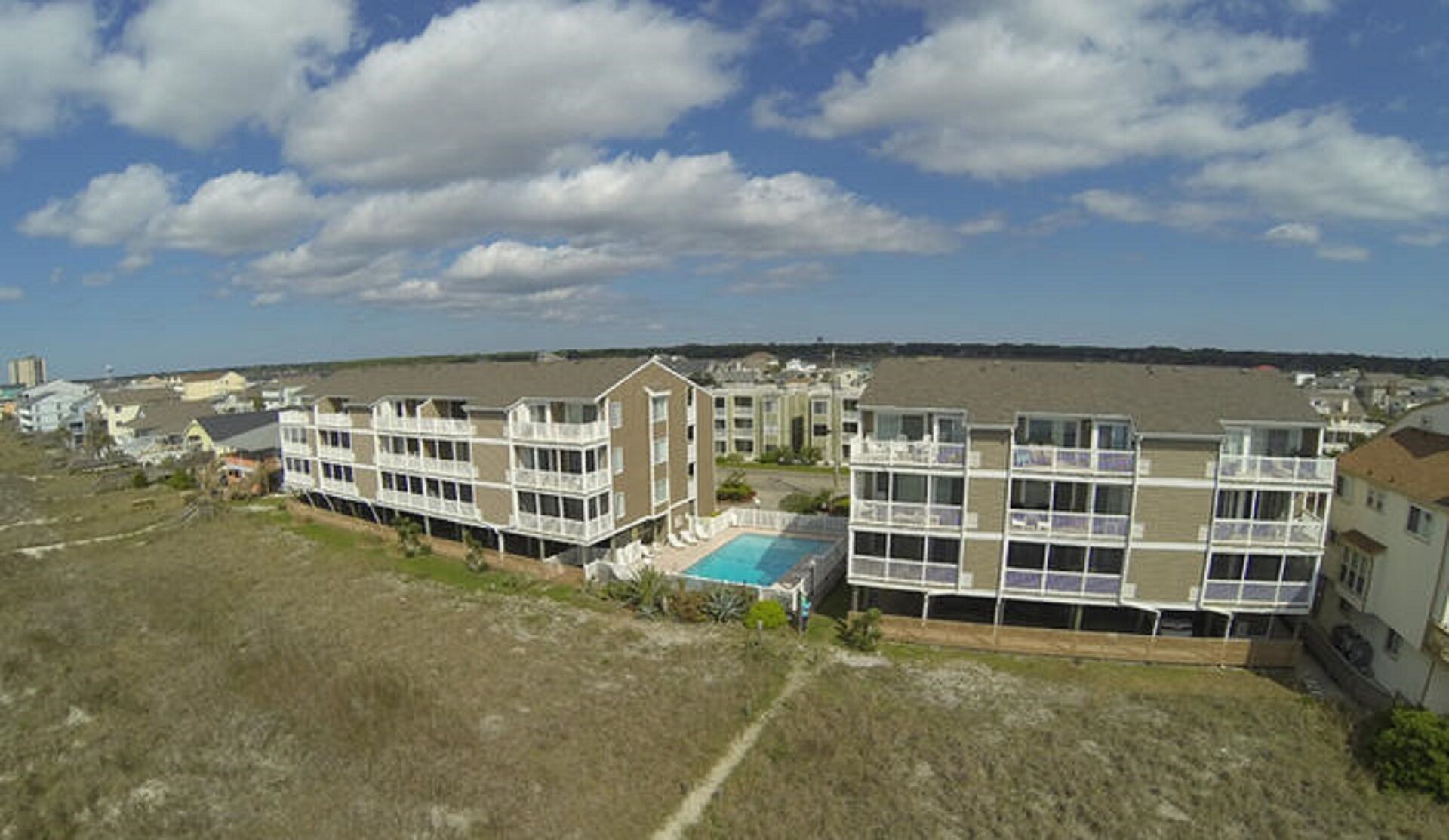 A multi-story residential building with a swimming pool and a view of the beach.