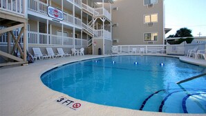 Una piscina con un indicador de profundidad de 3 pies, rodeada por un edificio con balcones y un letrero que dice "SUNVILLAS".