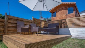 A wooden deck with wicker furniture and a large umbrella.