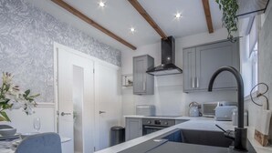 A modern kitchen with grey cabinets, a black range hood, a built-in oven, and a sink with a black faucet.