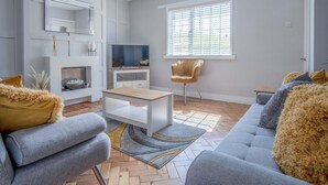 A modern living room with a sofa, a coffee table, a TV, and a fireplace.