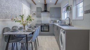 A modern kitchen with grey cabinets, a built-in oven, a dishwasher, and a dining area with a marble table and chairs.