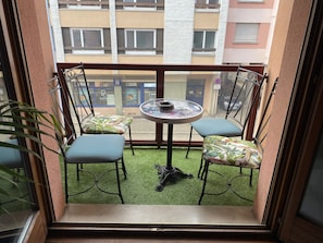 Enjoy a peaceful retreat on this balcony with a table for four and comfortable seating.