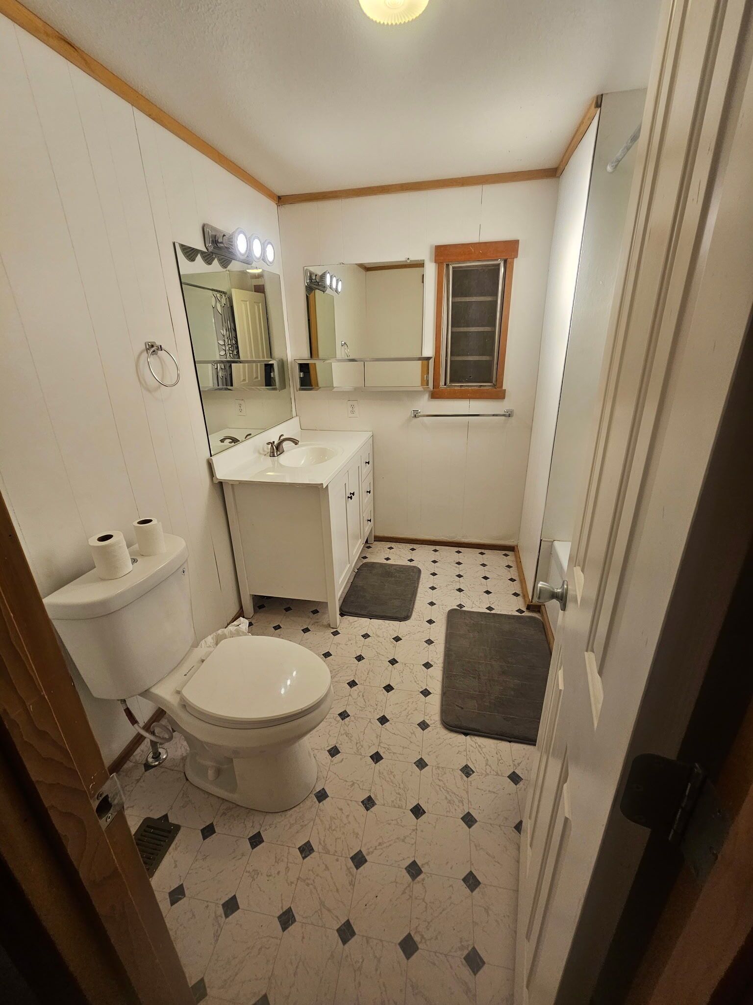 A compact bathroom with a toilet, sink, and mirror.