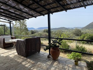 A covered outdoor seating area with wicker furniture and a potted plant. - Cosy Calm Cottage in Olive Trees With sea View (Ermionida)
