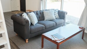 A living room with a grey sofa, patterned cushions, a wooden coffee table, and a rug. - Beautiful new guest cottage, perfect for families! (Hayden)
