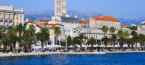 A waterfront promenade with palm trees, historic buildings, and a prominent tower. - Impeccable 1-bed Apartment in Center of Split (Split)