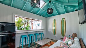 Een keuken met een zwarte koelkast, turquoise krukken, een houten tafel en een raam met uitzicht op palmbomen.