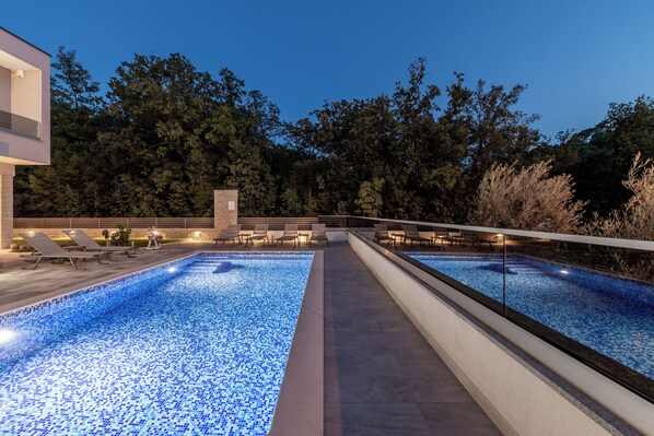 Zona de piscina con dos albercas, sillas de descanso y un sendero.