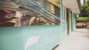 A hotel entrance with a teal facade and a large mural. - Hotel la Caracola Suances (Suances)