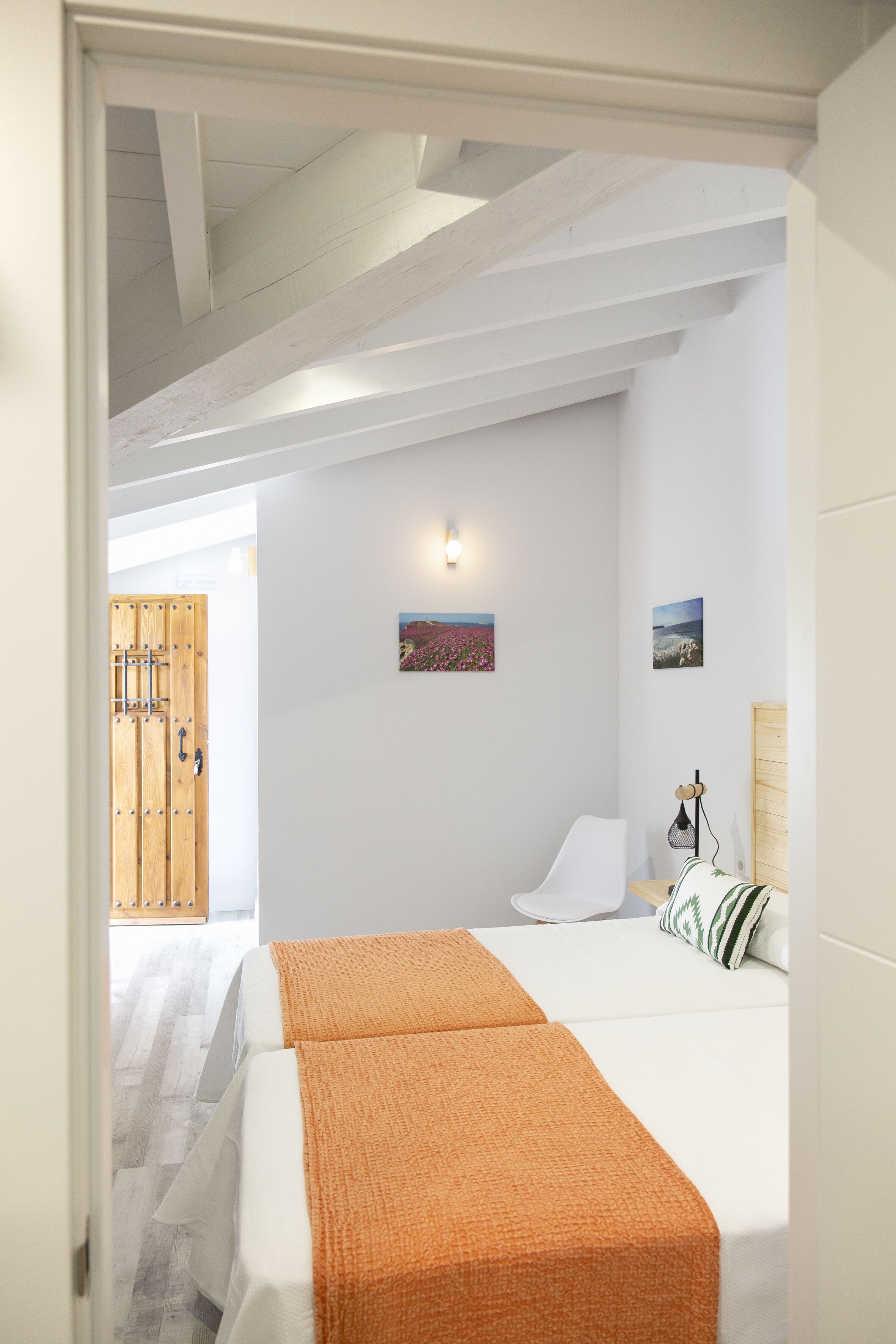 A bedroom with a bed, a wooden door, and a wall-mounted light fixture.