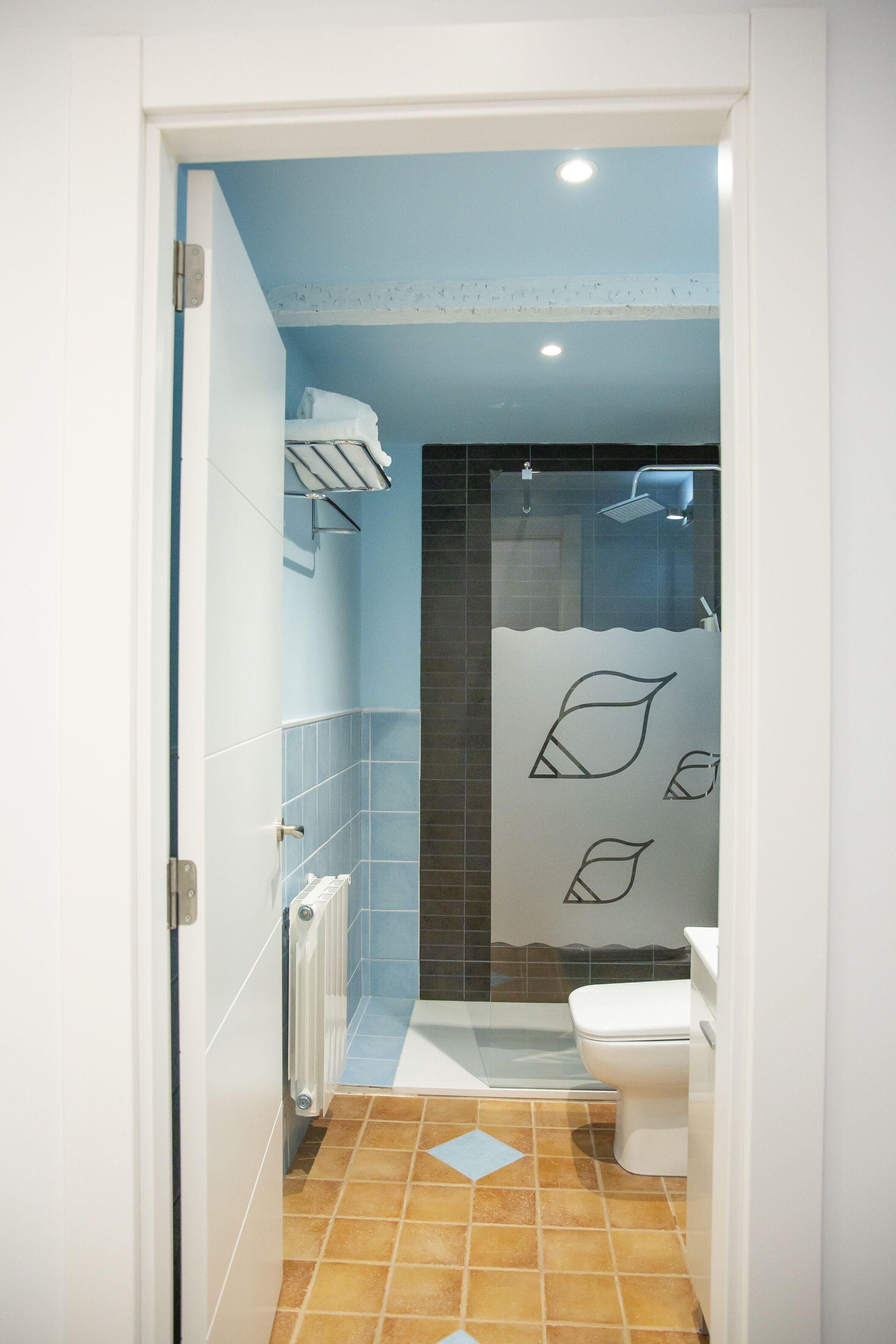 Un baño con ducha, inodoro y un perchero para toallas.