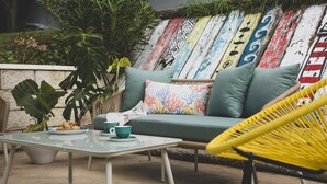 A cozy outdoor seating area with a green sofa, a yellow chair, and a glass table. - Hotel la Caracola Suances (Suances)