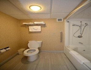 Une salle de bain comprenant des toilettes, une douche avec un pommeau de douche amovible et un porte-serviettes avec des serviettes.