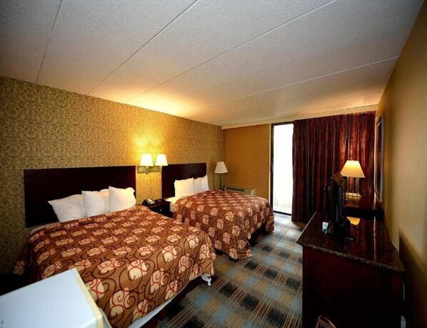 Une chambre d’hôtel avec deux lits, un bureau et une fenêtre avec des rideaux.