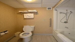 Une salle de bain comprenant des toilettes, une douche avec un pommeau de douche amovible et un porte-serviettes avec des serviettes.