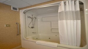 Une salle de bain équipée d’une baignoire, d’une douche et d’une barre d’appui.