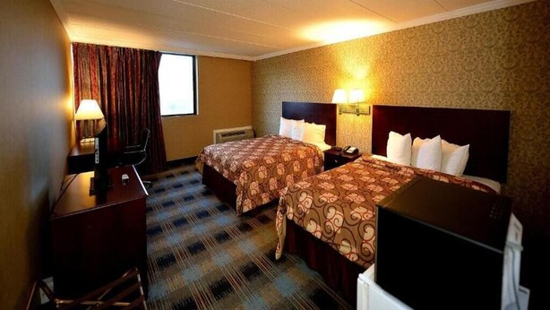 Une chambre d’hôtel avec deux lits, un bureau, une chaise et une télévision.