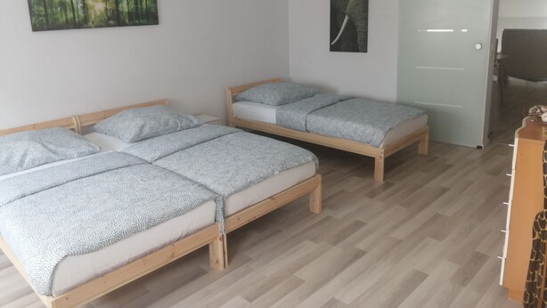 A room with two wooden beds, a door, and a small desk. - Bright 2 room apartment 25min to Europapark (Lahr/Schwarzwald)