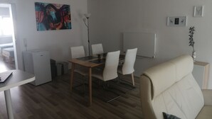 A modern living room with a dining area, a sofa, a coffee table, and a painting on the wall. - Bright 2 room apartment 25min to Europapark (Lahr/Schwarzwald)