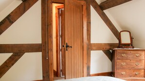 Une chambre avec une porte en bois, une commode à tiroirs et une couvre-lit à motifs.