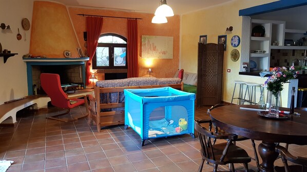 Un salon accueillant avec un parc pour enfants bleu, une table de billard et un coin repas comprenant une table et des chaises en bois.
