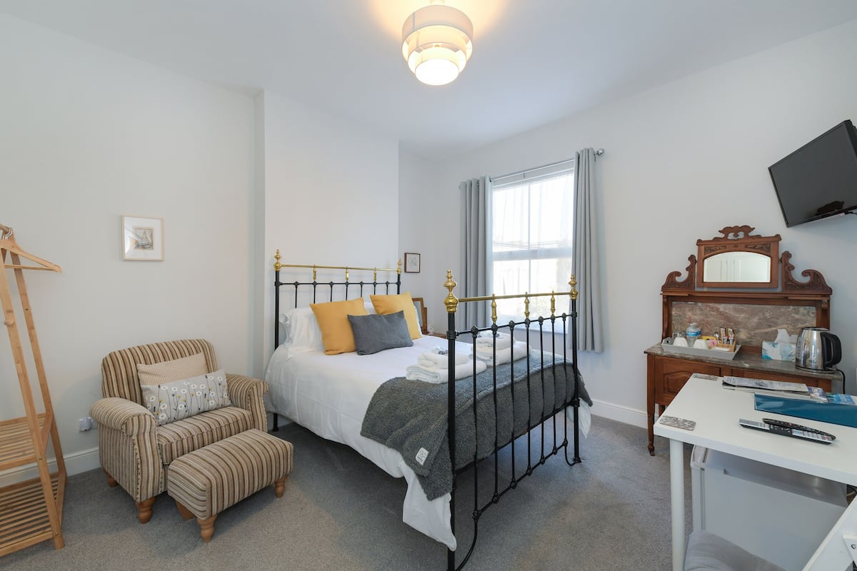A bedroom with a bed, a chair, a desk, and a television.