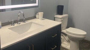 Un bagno con un lavandino bianco, mobili scuri, uno specchio e un water.